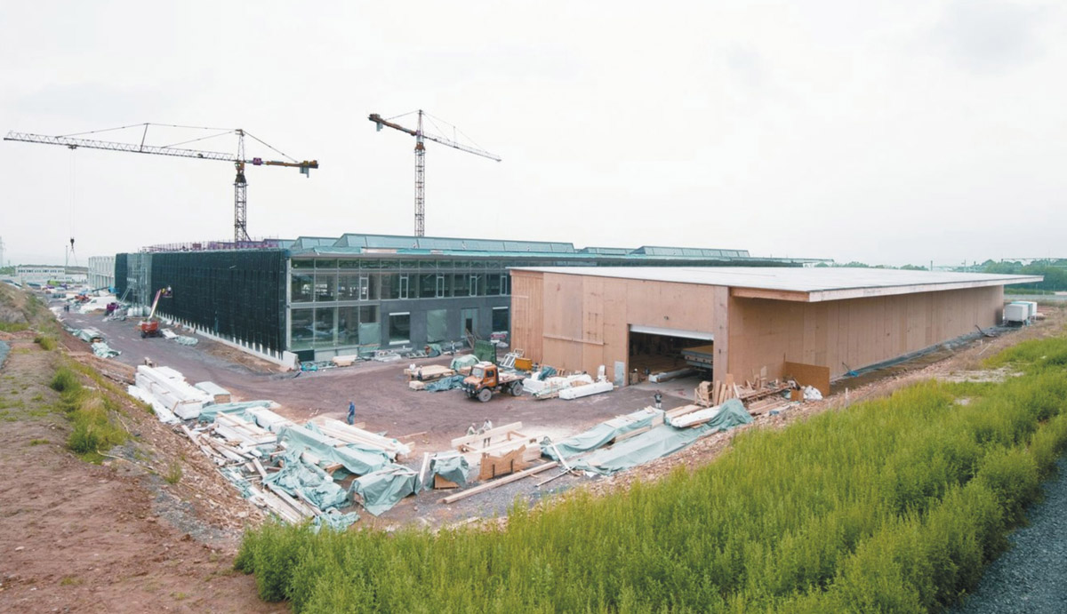 Prefabrikované stěny a stropy byly vyráběny v dočasném terénním závodě (na fotografii v popředí)