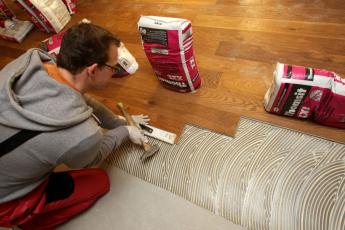 Prkno položené v lepidle je nakonec přiklepnuto kladivem