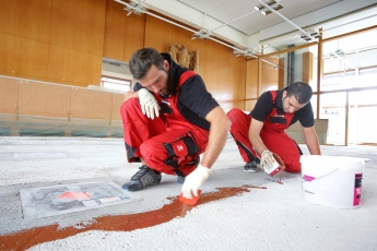 Pro lepší přilnavost následně nanášené vyrovnávací hmoty a vytvoření mimořádně pevného spojení podkladu se stěrkou posypal tým firmy Waschke ještě čerstvou pryskyřici vysušeným křemičitým pískem o zrnitosti 0,3–0,7 mm