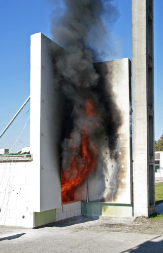 Obr. 10, 11: Velkorozměrová zkouška zateplení dle ISO 13 785-2 s výkonem cca 3 MW v průběhu a po skončení zkoušky. Výška plamene by přímo zasahovala do oken dalšího podlaží, jenže na vzorku dle uvedené metodiky žádná nejsou.