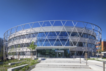 Předvěšený obvodový plášť z profilovaného hliníkového plechu doplňují průběžná pásová okna, po obvodu celého objektu je ocelová konstrukce, která slouží k zavěšení nerezové sítě, tvořící podporu pro popínavé rostliny