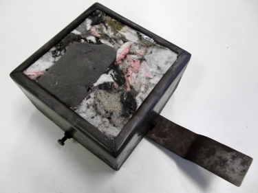 Obr. 5: Zkušební vzorek materiálu Stered o rozměrech 100x100x50 mm osazený v upevňovacím rámu; a – před zkouškou; b – po zkoušce