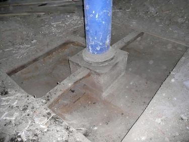 Realizace zpevnění podloží pod roznášecími bloky ŽB sloupů ve 2. NP, přenášejících zatížení do zesilovaných pilířů v 1. NP – původní stav s kamenným blokem základu a dřevěným sloupem s ocelolitinovou patkou (vlevo) a zpevňující injektáž centrální části zhlaví pilířů pryskyřicí CarboPur WF z úrovně 2. NP (vpravo)