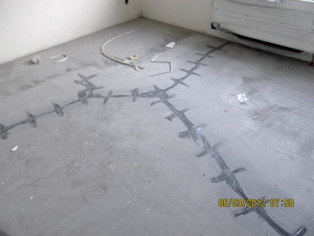 Obr. 7: Smršťovací trhliny v podkladní cementové mazanině, dodatečně sanované gravitační epoxidovou injektáží a tzv. sešitím