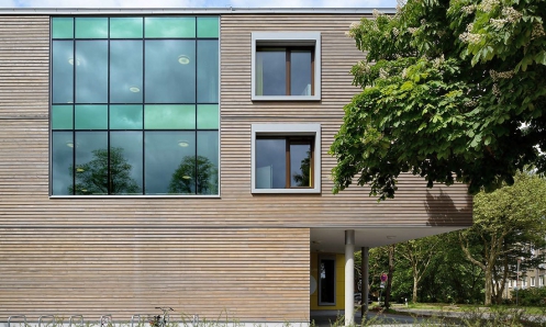 Obr. 6–9: Školicí centrum Tor zur Welt (Brána do světa) v Hamburku. Všechny budovy jsou hybridní. Mají železobetonové skelety a fasáda byla vytvořena jako dřevostavba z prefabrikovaných dřevěných panelů. Vnější opláštění budovy přitom tvoří cementovláknité desky Fermacell Powerpanel HD jako nosné desky omítky. Zavěšené prvky vnějších stěn (konstrukce na bázi dřeva) byly zkombinovány s provětrávaným fasádním obkladem z šedě lazurovaného modřínového dřeva.