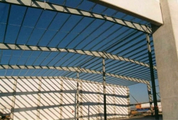 Obr. 7a: Pohled na štíhlou konstrukci haly, zjevně nevyhovující tenké stykové desky, zcela nadměrně zvlněné stěny nosníků celkově chybná výroba