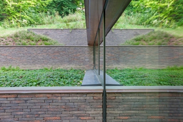 Obr. 8: Na severní straně definují jednotlivé úrovně budovy cihlové zdi, korespondující stoupající terén. Velký podíl denního světla vstupuje do podzemního podlaží skrze sloupko-příčkovou fasádu ze systému Schüco (AWS 75.SI).