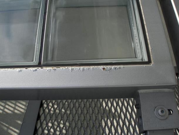 Obr. 3: Příklad podkorodování okraje nátěrového systému na obdobné konstrukci, který nebyl aplikován na celém povrchu profilu ocelového rámu, opatřeného nejprve vrstvou žárového zinku