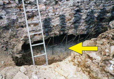 Obr. 14: Stav původních základů – mohutná kaverna pod dolní hranou základu (šipka)