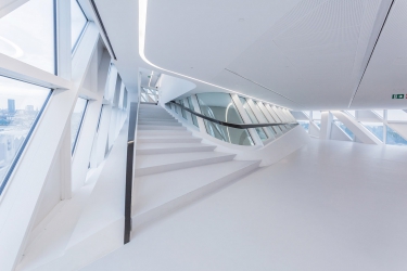 Směs prosklených a neprůhledných fasádních jednotek opticky zkresluje objem budovy, jejíž transparentní povrch se mění v závislosti na intenzitě denního světla