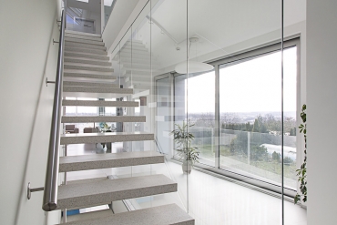 Schodiště je součástí obytných prostor – má vlastní okno ve střeše a jeho teracové stupně levitují mezi pevnou a prosklenou stěnou