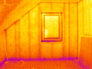 Termokamera odhalí nejslabší místa konstrukce z pohledu tepelněizolačních vlastností pomocí kontrastního barevného zobrazení. Pohled na štítovou stěnu dřevostavby pomocí termokamery – jednotlivé materiály použité v sendvičové konstrukci mají odlišné tepelněizolační vlastnosti. Problematické je v tomto případě napojení stěny na stropní konstrukci, kde je únik díky tepelnému mostu největší.