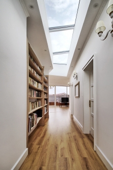 Ze schodiště vedou vstupní dveře do haly s knihovnou, která je nasvětlena střešním světlíkem