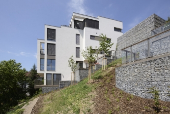 Na terén navazují domy terasami a zídkami z gabionů