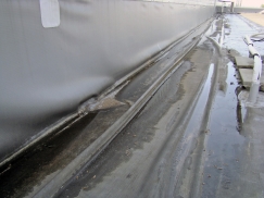 Obr. 4: Havarovaný detail střechy v důsledku vytržení lišty u paty atiky znamená deformaci fólie, znesnadnění odtoku vody