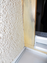 Obr. 4: Chybně zabudovaný okenní rám (dokončená fasáda po osmi měsících), zdegradovaná montážní pěna – zůstala porézní, což je následek chybné aplikace bez zvlhčení ostění. Dochází ke kondenzaci v připojovací spáře, následně ke zvýšení vlhkosti nad 18 % a separaci lazury a vzniku plísně pod lazurou.