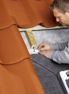 Hydroizolační límec. Po osazení střešního okna se na něj přilepí hydroizolační fólie a přetáhne se přes laťování do sousedního pole. V horní části okna se uloží drenážní žlábek.