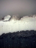 Obr. 19: Detailní snímek nekryté části zkušebního vzorku – příčný řez. Na snímku jsou patrné známky degradace materiálu.