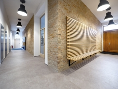 Chodba, kde dominuje režné zdivo, propojuje všechny tři části objektu