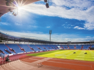 Nové kryté tribuny uzavírají sportovní ovál po stranách původní tribuny