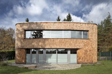 Pro fasádu měli autoři projektu více variant řešení, nakonec se rozhodli pro šindele, které dobře kopírují měkký tvar stavby