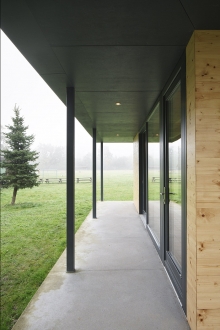 Krytý ochoz chráněný přesahem střechy u komunitní místnosti