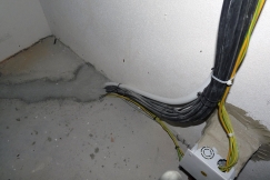 Obr. 14–16: Největší netěsnosti zjištěné při kontrolním testu vzduchotěsnosti obálky budovy – nevhodně zpracovaný detail parapetu u rohového okna, netěsnost kolem svazku kabelů a proudění vzduchu neutěsněnými chráničkami kabelů.