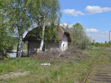 Bývalý strážní domek se nachází severovýchodně od nástupiště. Fasádou i polovalbovým zastřešením reaguje na výpravní budovu.
