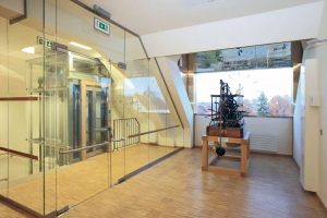 Za vikýřem s hodinami na skleněné ploše je historický hodinový stroj