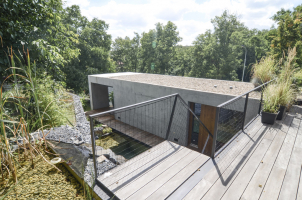 Hmotu domu odlehčují volné přesahy, prosklené plochy a terasy zapuštěné do železobetonového tělesa