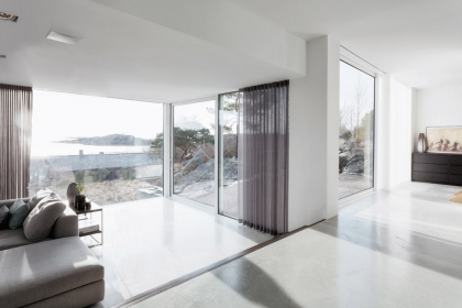 Pevná i posuvná křídla se skly od podlahy až ke stropu a s kolejnicemi zapuštěnými v podlaze nabízejí panoramatické výhledy na okolní krajinu (systémy Schüco FW 50+.HI a Schüco ASS 50)