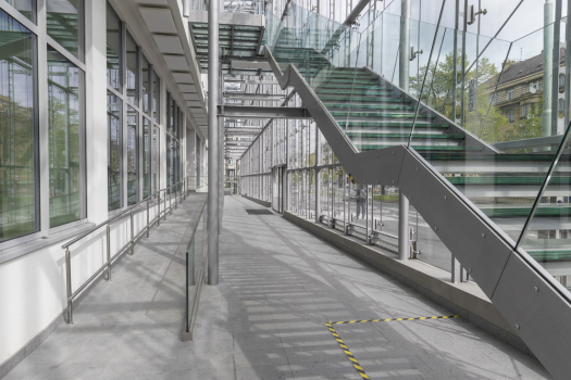 Předsazená celoskleněná konstrukce obvodové stěny vytváří meziprostor pro požární úniková schodiště, navíc má příznivý vliv na vnitřní mikroklima budovy a chrání ji před dopravním hlukem