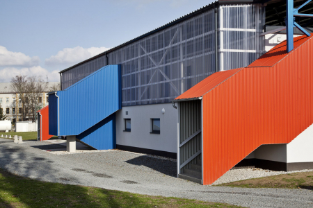 Červená schodiště vedou na tribunu, modrá z interiéru do druhého patra