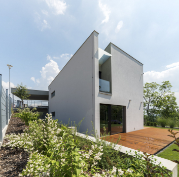 Obytná část domu má bílou omítku, velkoformátová okna zajišťují kontakt se zahradou a výhledy na Slánskou horu a klášterní kostel