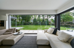 Neotvíravá prosklená stěna o ploše bezmála 13 m² téměř dokonale odstraňuje vizuální hranici mezi obytným prostorem a zahradou (Schüco AWS 75.SI)