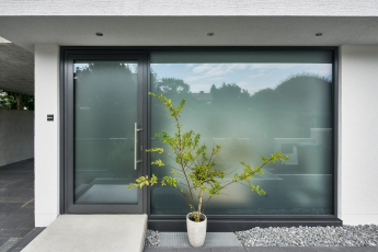 Soukromí i přirozené osvětlení. Vchod orientovaný do ulice (fasáda Schüco FWS 35 PD.SI a dveřní systém Schüco ADS 75.SI).