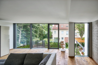 Konstrukce prosklené fasády v hliníkových rámech se zabudovaným otvíravým křídlem, který zvenku chrání bezrámové hrazení z laminovaného bezpečnostního skla, zaručuje výbornou tepelnou izolaci (Schüco FWS 35 PD.SI s trojitým izolačním sklem)