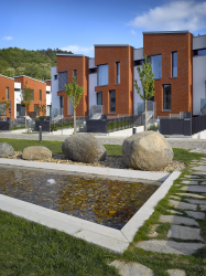 Zešikmené střechy mají úžlabí kolmo k uliční frontě. Bělostnou omítku ustupujících částí doplňuje keramický obklad.