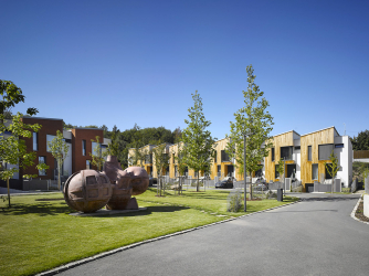 Na řešení veřejného prostoru a zeleně kladl investor mimořádný důraz: parkovou část dělí balvany a drátěné klece, porostlé zelení, travnaté vyvýšeniny byly osázeny vzrostlými stromy