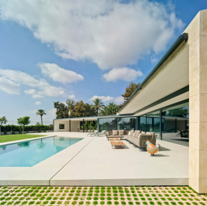 Sedlová střecha s mírným sklonem přesahuje na straně směrem k bazénu hmotu budovy, a nabízí tak další zastínění