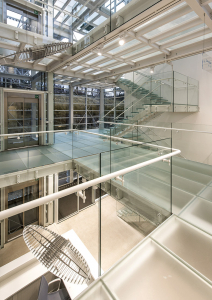 Skleněné schodiště a skleněné podlahy propouštějí sluneční paprsky celou halou a dodávají tak interiéru lehkost