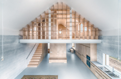 Interiér domu korunovaný obloukem v hřebeni střechy je jedním spojitým prostorem rozděleným vzdušnou knihovnou