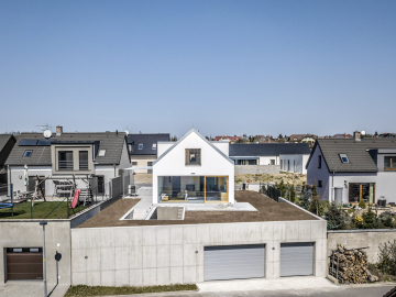 Garáž vyrovnávajíci vyškový rozdíl mezi přiléhajícími ulicemi tvoří podstavu domu