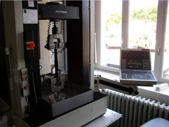 Obr. 1: Trhačka pro zkoušení pevnosti hydroizolačních materiálů, a to i ve spojích (v pozadí je patrná klimatizační komora pro modelaci různých teplotních parametrů při zkoušení)