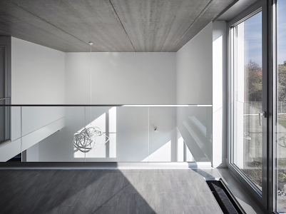 Kombinace bílé hladké omítky se světlou plechovou střechou a hliníkovými okny se propisuje i do interiéru, do světlých neutrálních odstínů podlahy a nábytku