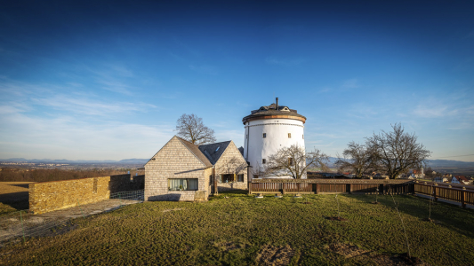 Novostavba obytného domu svou velikostí neohrožuje dominantu bílé válcové hmoty větrného mlýna. Nenarušuje ani pohledové osy, které k němu směřují.