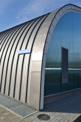 Na obloukové části vnější stěny a střešním plášti jsou lakované hliníkové profily, další část fasády kryjí plechové kazety a polykarbonátový obklad