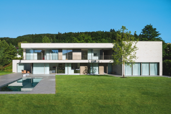 Zadní fasáda podlouhlé stavby se v obou výškových úrovních otevírá směrem do zahrady díky posuvným systémům (Schüco ASS 77 PD.SI)