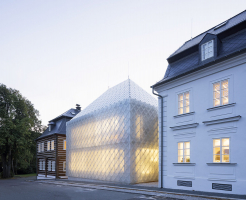 Novostavbu pokrývají na míru vyvinuté skleněné tvarovky, jež vycházejí z formátu a kladení břidlicových desek užívaných na štítech a střechách v regionu. Sklon a výška hřebene valbové střechy odpovídají typickému tvaru sousedních domů