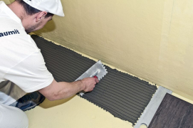 Po vyzrání hydroizolačního souvrství (cca 24 hod.) je možné lepit obkladové prvky – vždy je nutné vybrat vhodný typ lepidla, který je odvislý od celého spektra požadavků. Pro čistě interiérové lepení je možné použít lepicí hmotu Baumit Baumacol Basic. Lepicí maltu je nutné nanášet na podklad ve 2 pracovních krocích. V prvním pracovním kroku nanést tenkou kontaktní vrstvu. Na ještě mokrou vrstvu nanést ve druhém pracovním kroku ozubenou stěrkou odpovídající vrstvu lepicí hmoty pod úhlem 45–60°